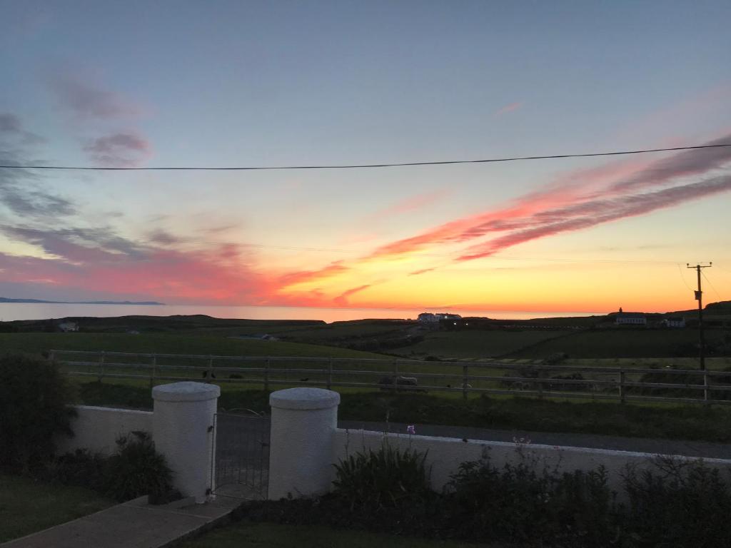un coucher de soleil sur un champ avec une clôture et le ciel dans l'établissement Carnside Guest House, à Bushmills