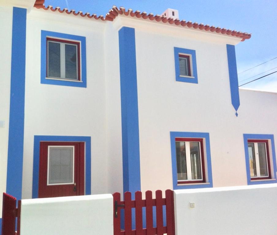 ein weißes und blaues Haus mit einem roten Zaun in der Unterkunft Casa da Âncora - Comporta in Comporta