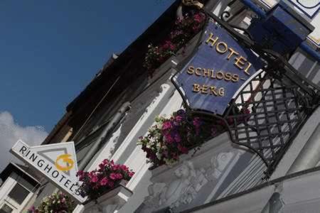 a sign on the side of a building with flowers at Ringhotel Schlossberg in Neustadt