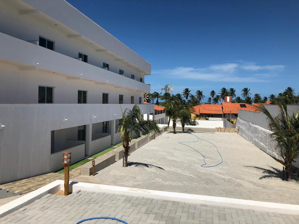 une cour d'un bâtiment avec des palmiers et un terrain de basket-ball dans l'établissement Vilas Blancas, à Cumbuco