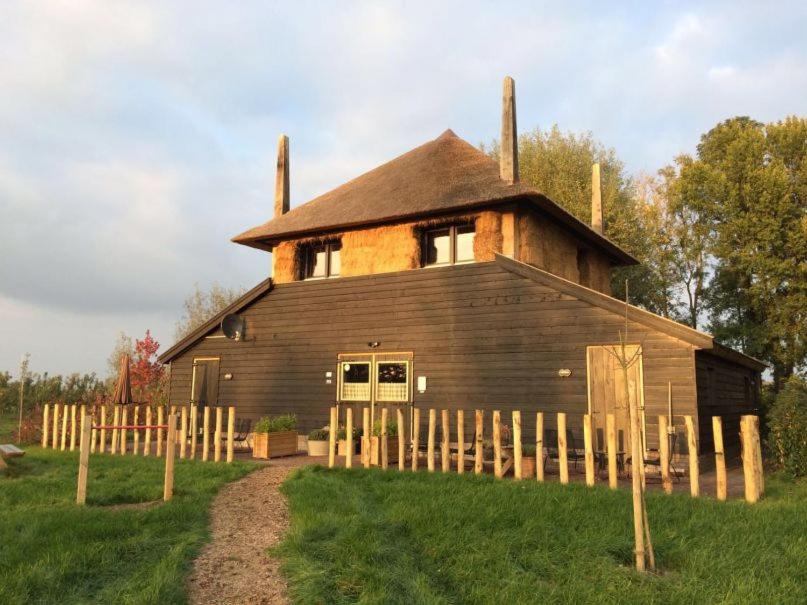 un granero de madera grande con una valla delante en De Steltenberg in de Betuwe en Zoelen