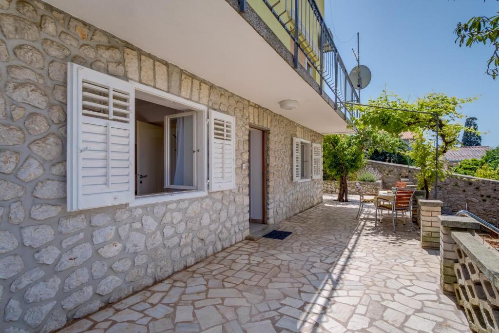 a stone house with a window and a patio at SheShe in Mali Lošinj