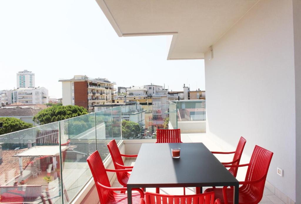 einen schwarzen Tisch und rote Stühle auf dem Balkon in der Unterkunft Dainese Apartments, Casa Miriam in Lido di Jesolo