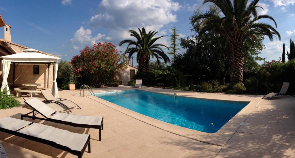 a swimming pool with chairs and trees and a house at Maison Provençale in Flayosc