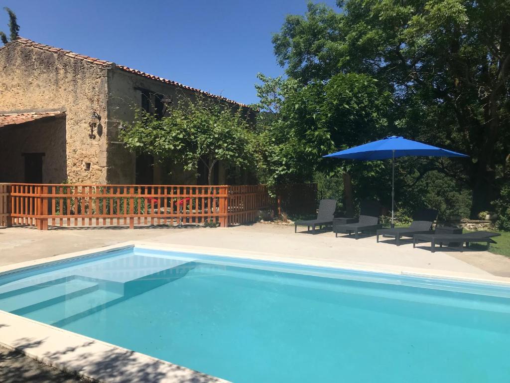 einen Pool mit einem Sonnenschirm, 2 Stühlen, einem Tisch und einem Sonnenschirm in der Unterkunft Hameau de Montcabirol in Mirepoix