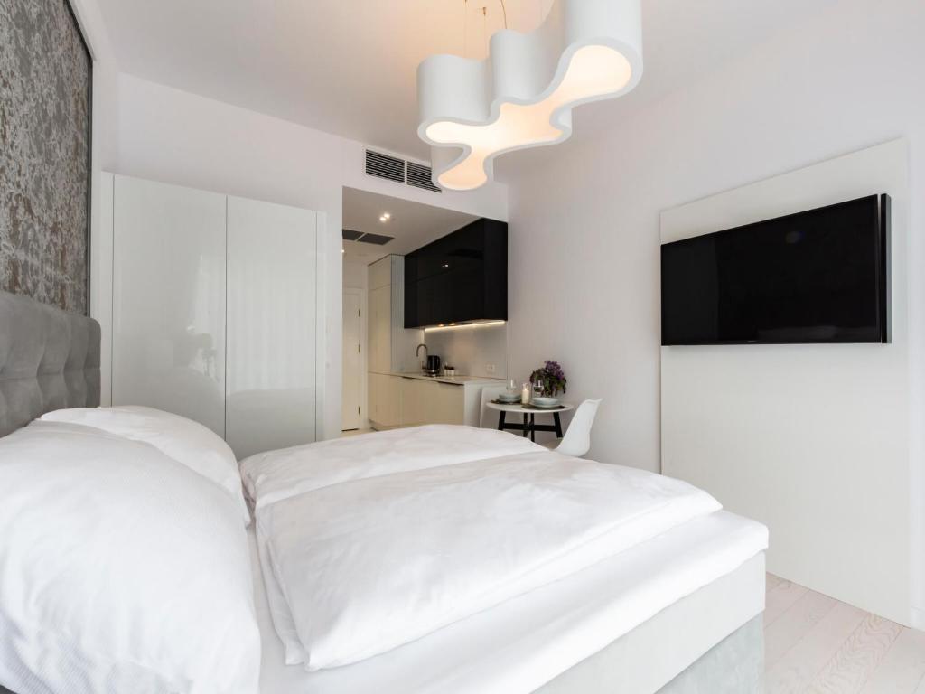 biała sypialnia z białym łóżkiem i telewizorem w obiekcie VacationClub – Dune B Apartament 3.23 w mieście Mielno
