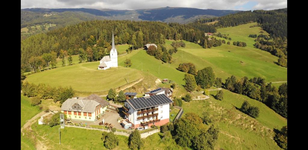 an aerial view of a house on a hill with a church at Gasthof Gutmann in Eberstein