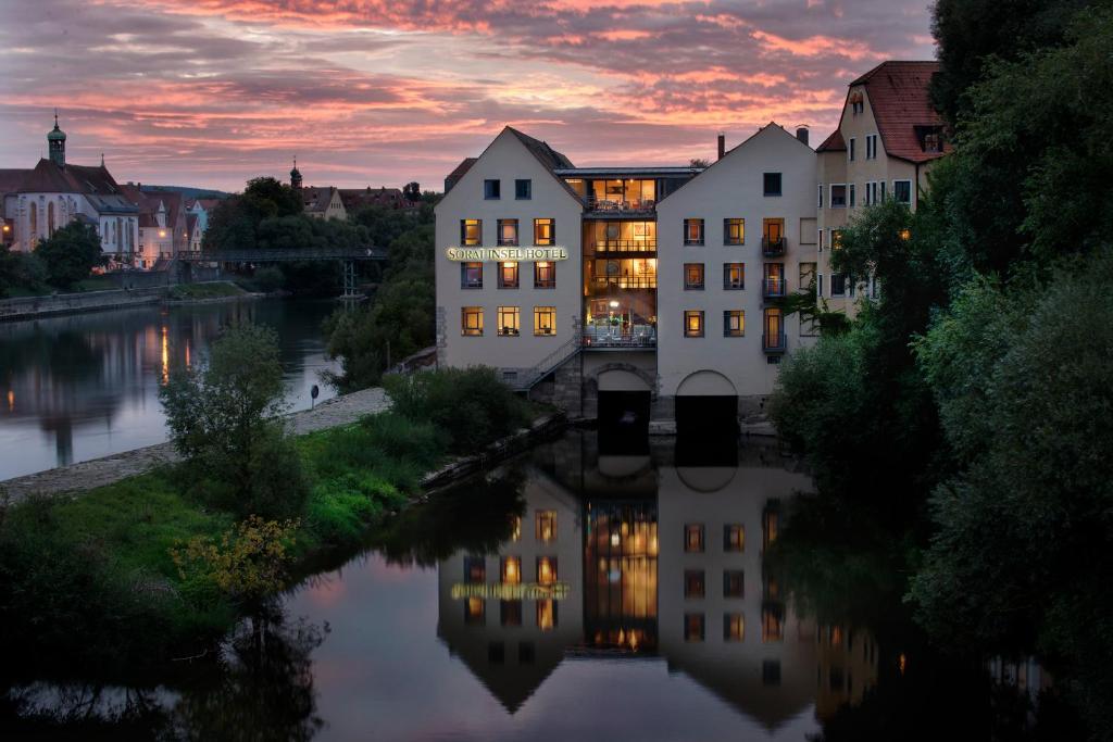Blick auf eine Stadt mit Fluss und Gebäuden in der Unterkunft SORAT Insel-Hotel Regensburg in Regensburg