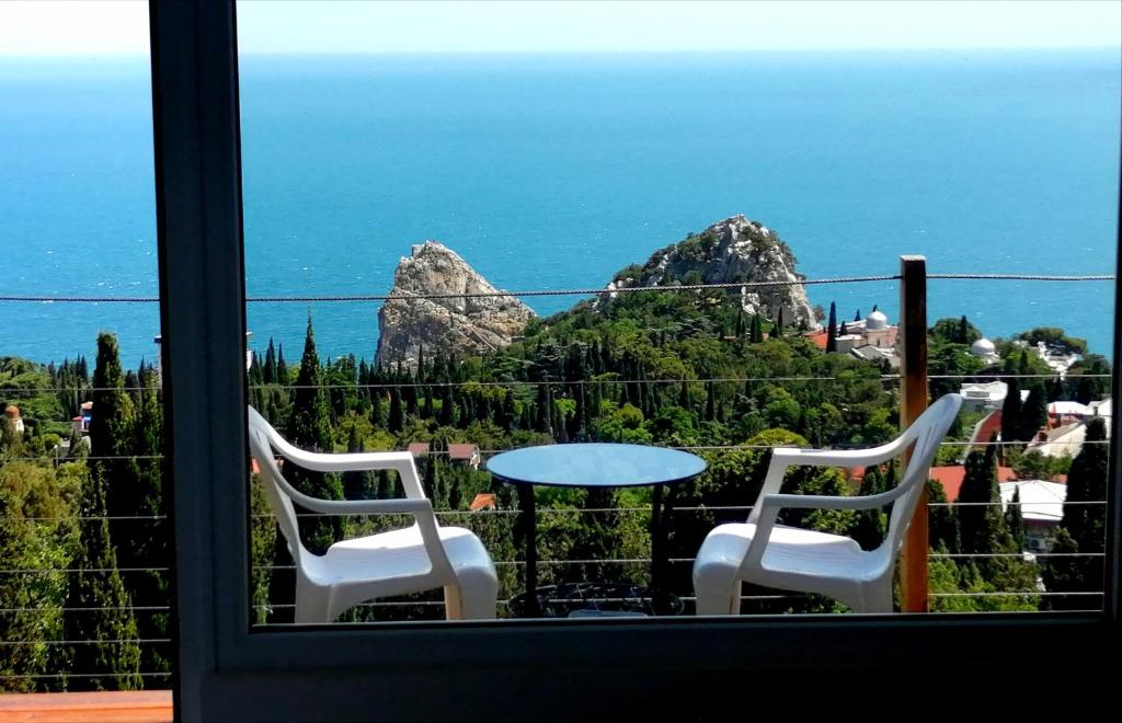 two chairs and a table with a view of the ocean at Guest House Lesnaya Koshka in Simeiz