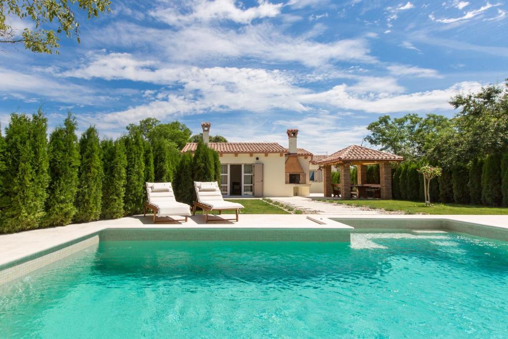 a swimming pool with two chairs and a house at Small old house in Nedeščina