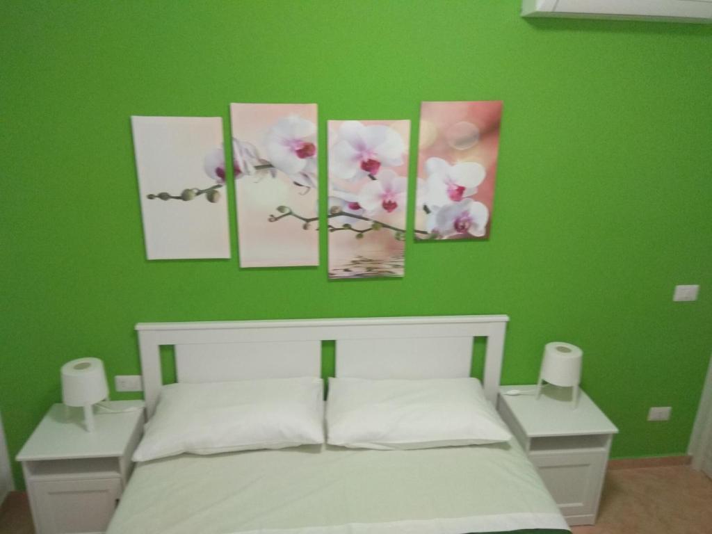 a green bedroom with four paintings on the wall at Sognando Lampedusa in Lampedusa