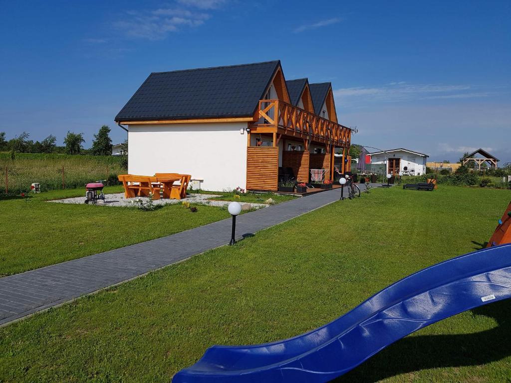 ein Haus mit einer blauen Rutsche vor einem Hof in der Unterkunft Domki Białe Zacisze in Mielenko