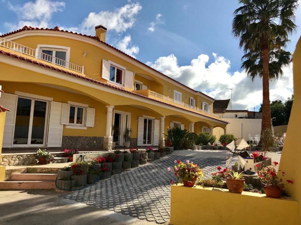 a yellow house with potted plants and a palm tree at Casa das Palmas in Óbidos