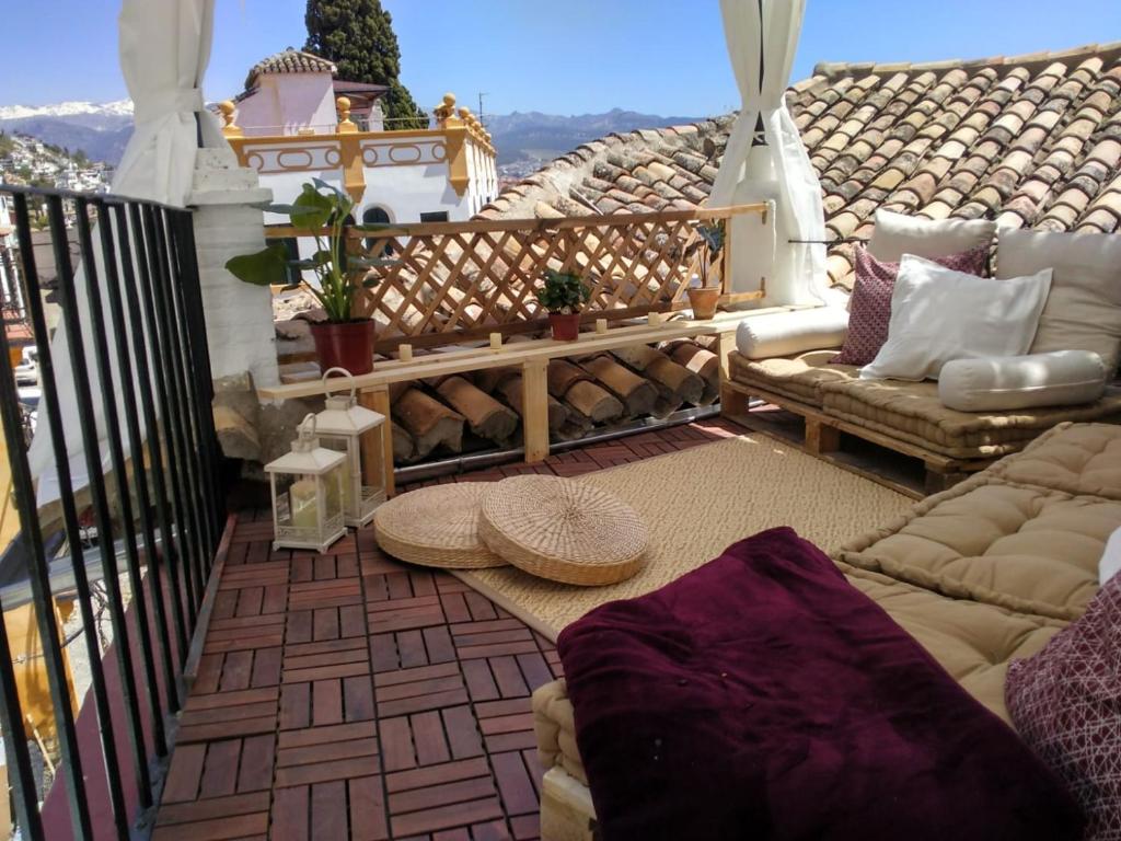 einen Balkon mit Sofa und Stühlen auf dem Balkon in der Unterkunft BENDITA CASA in Granada