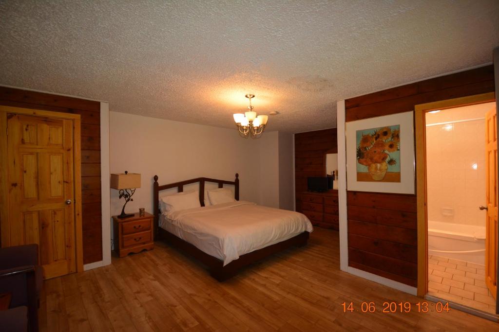 a bedroom with a bed and a bathroom with a tub at Auberge Alpine Inn in Sainte-Adèle