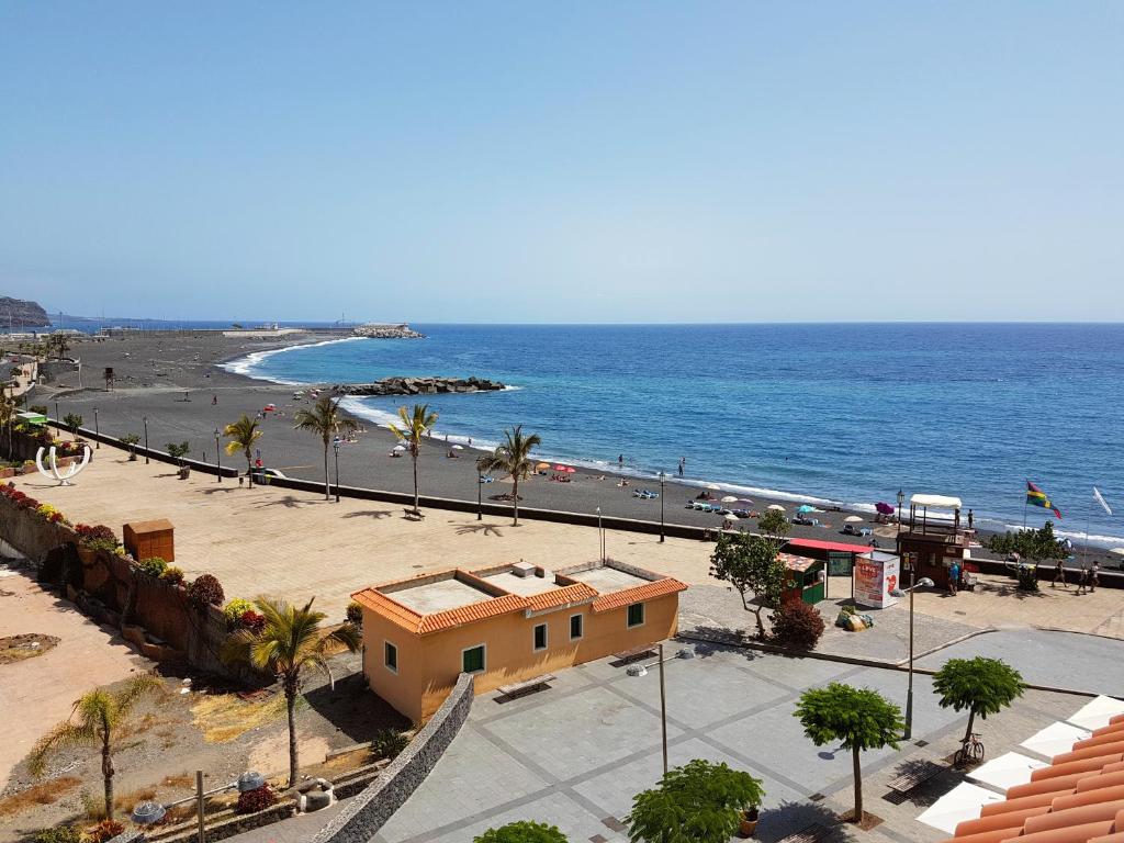 Blick auf einen Strand mit einem Gebäude und das Meer in der Unterkunft PLAYA PUERTO TAZACORTE Modern Beach Apartment in Tazacorte