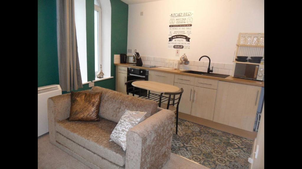 a living room with a couch and a kitchen at 1 Tŷ Mona Church Street Apartment in Llangefni