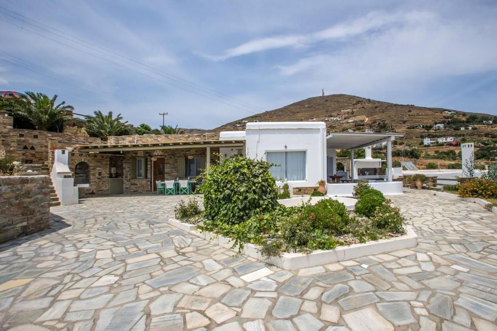 a house with a stone patio with a mountain in the background at Andrea's Tinos House in Agios Sostis