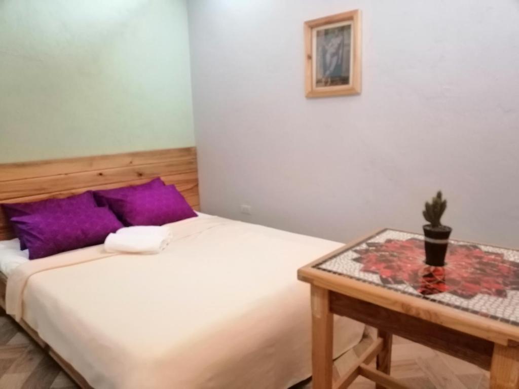 sypialnia z łóżkiem z fioletowymi poduszkami i stołem w obiekcie Sagada Lodging Home w mieście Sagada