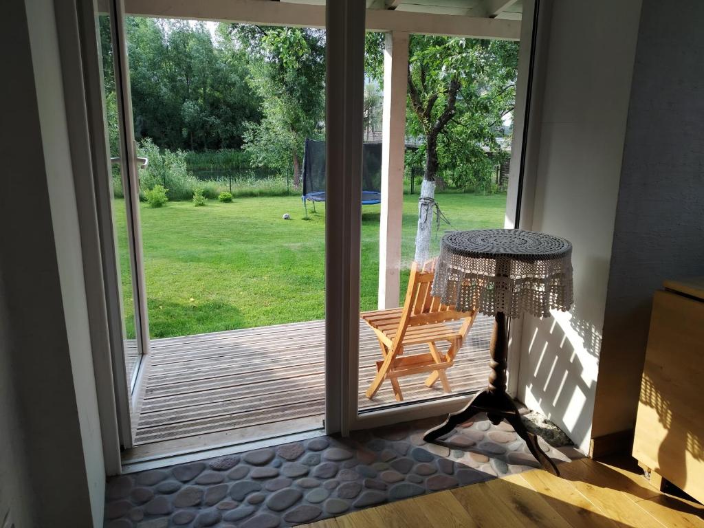 an open door to a deck with a chair and a table at River Side Studio, 9mi from Palanga, With sauna in Kretinga