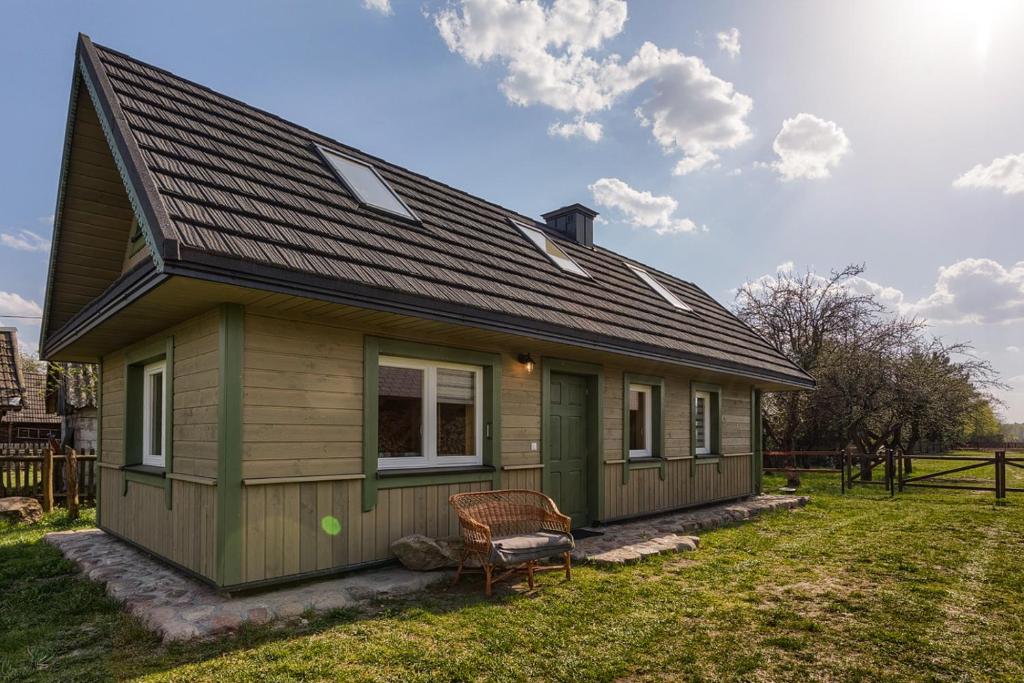uma pequena casa verde com um banco no quintal em KTA TARPAN Mały Domek em Masiewo