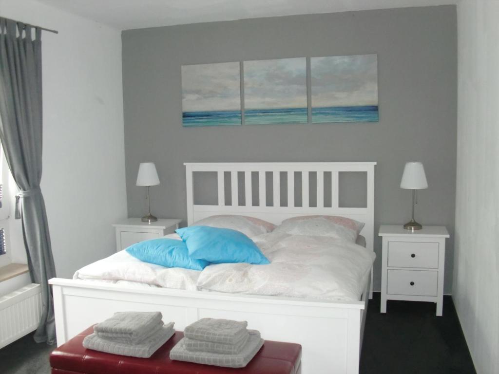 a white bed with two blue pillows on it at Schönes 2-Zi. App. 55 qm - voll möbliert - citynah in Elmshorn