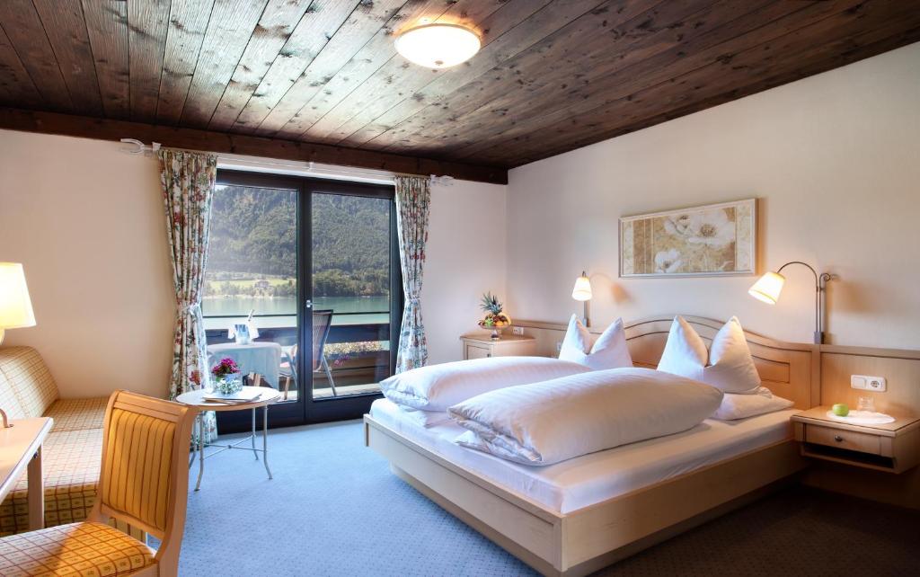 a bedroom with a large bed and a large window at Hotel Seewinkel in Fuschl am See