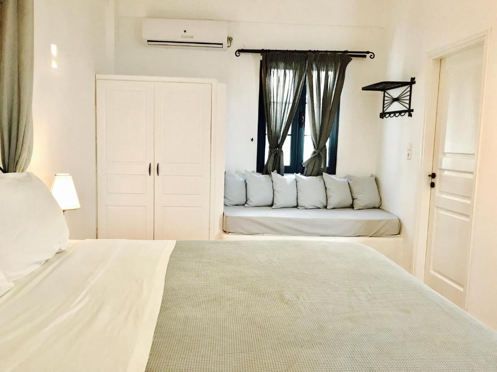 a white bedroom with a bed and a window at Sarakiniko View Studios in Mandrakia