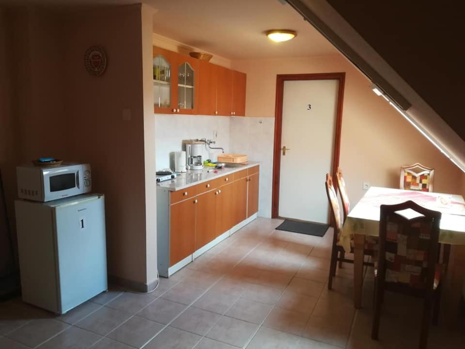 a kitchen with a table and a kitchen with a microwave at Karika Vendégház in Hajdúszoboszló