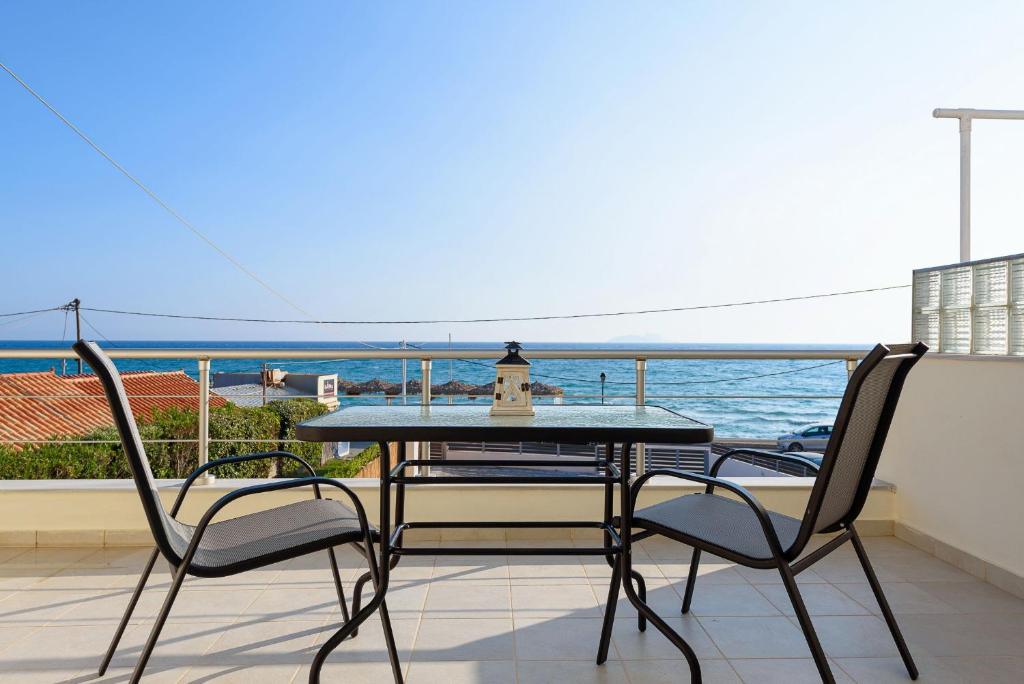 einen Tisch und Stühle auf einem Balkon mit Meerblick in der Unterkunft Coral Sea Studio in Kokkinos Pyrgos