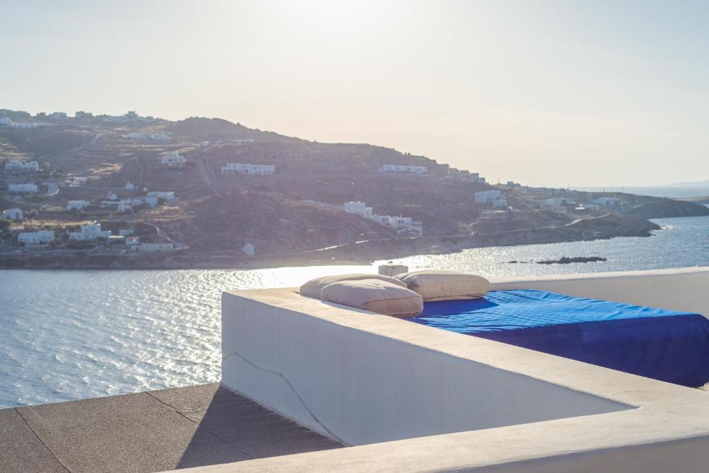 un letto sul bordo di un balcone affacciato sull'acqua di The Corfos Hills House a Ornos