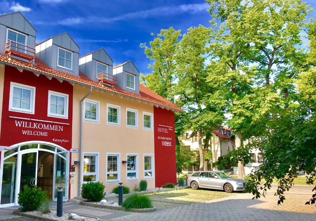 a red and orange building with a car parked in front at Bed&Breakfast Erber in Ismaning