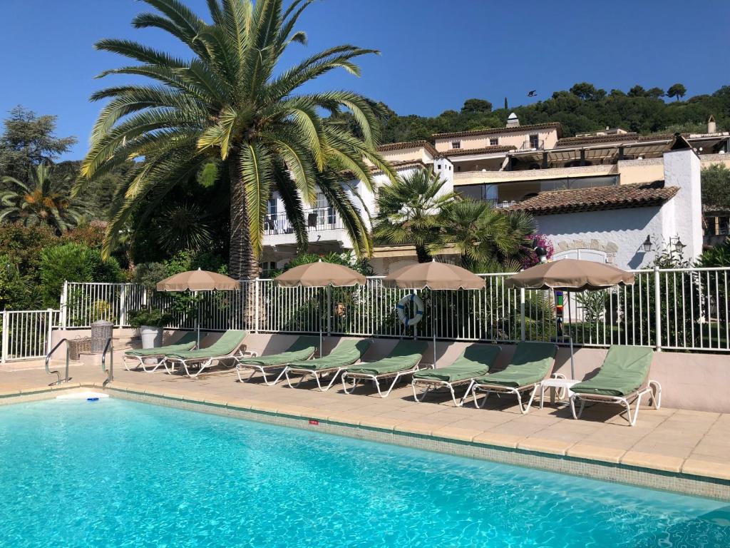 a swimming pool with lounge chairs and umbrellas at Hôtel & Restaurant Alain Llorca in La Colle-sur-Loup