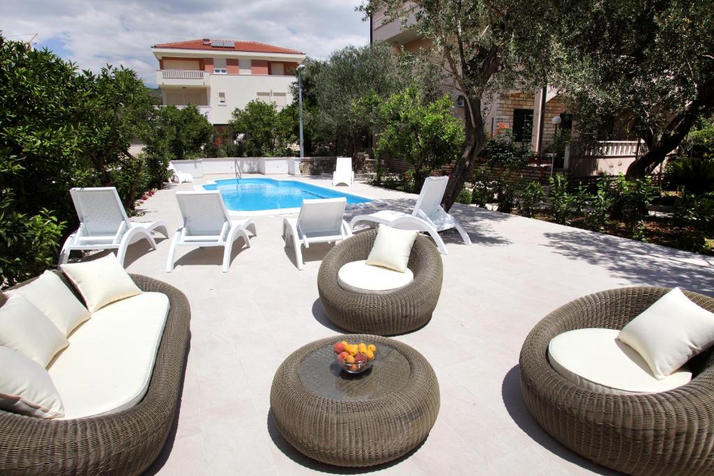 un patio con sillas de mimbre y una piscina en Villa Sun, en Seget Vranjica