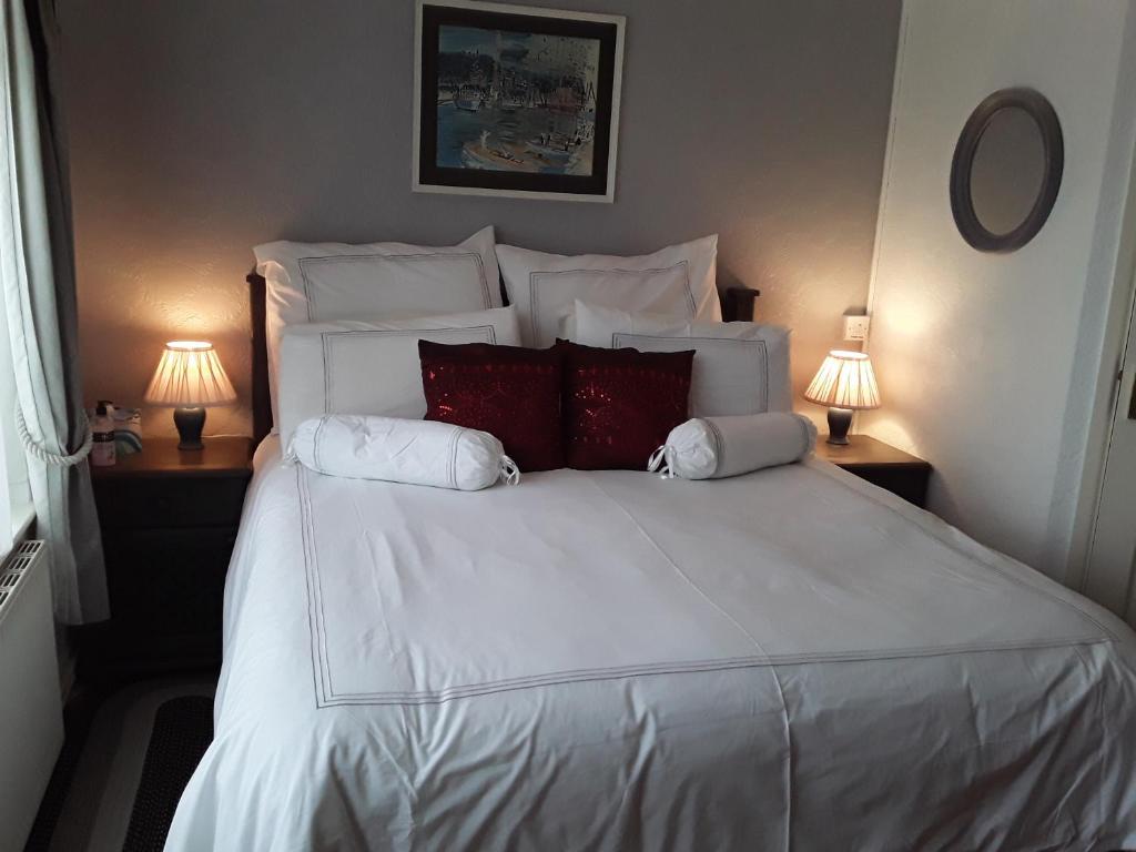 a bedroom with a large white bed with red pillows at The Willows in Tintagel