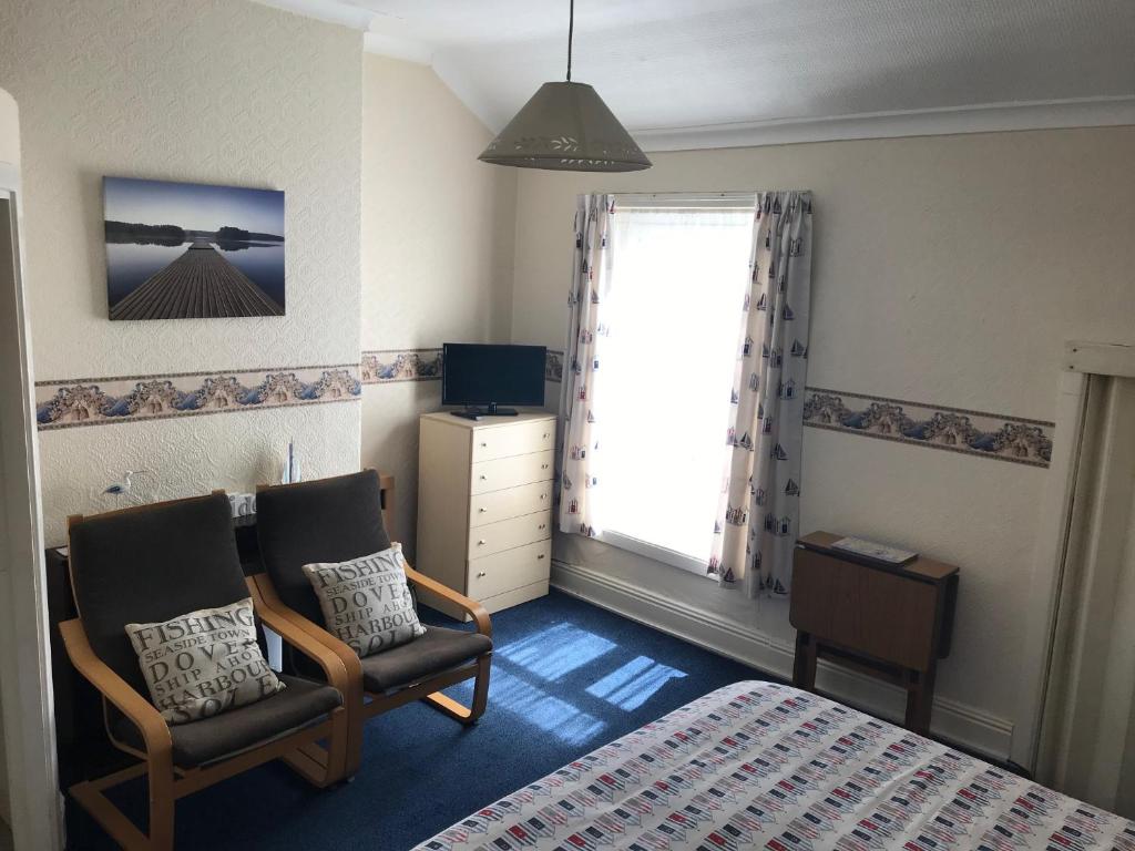 a bedroom with two chairs and a bed and a window at The Kathrene Holiday Flats in Fleetwood
