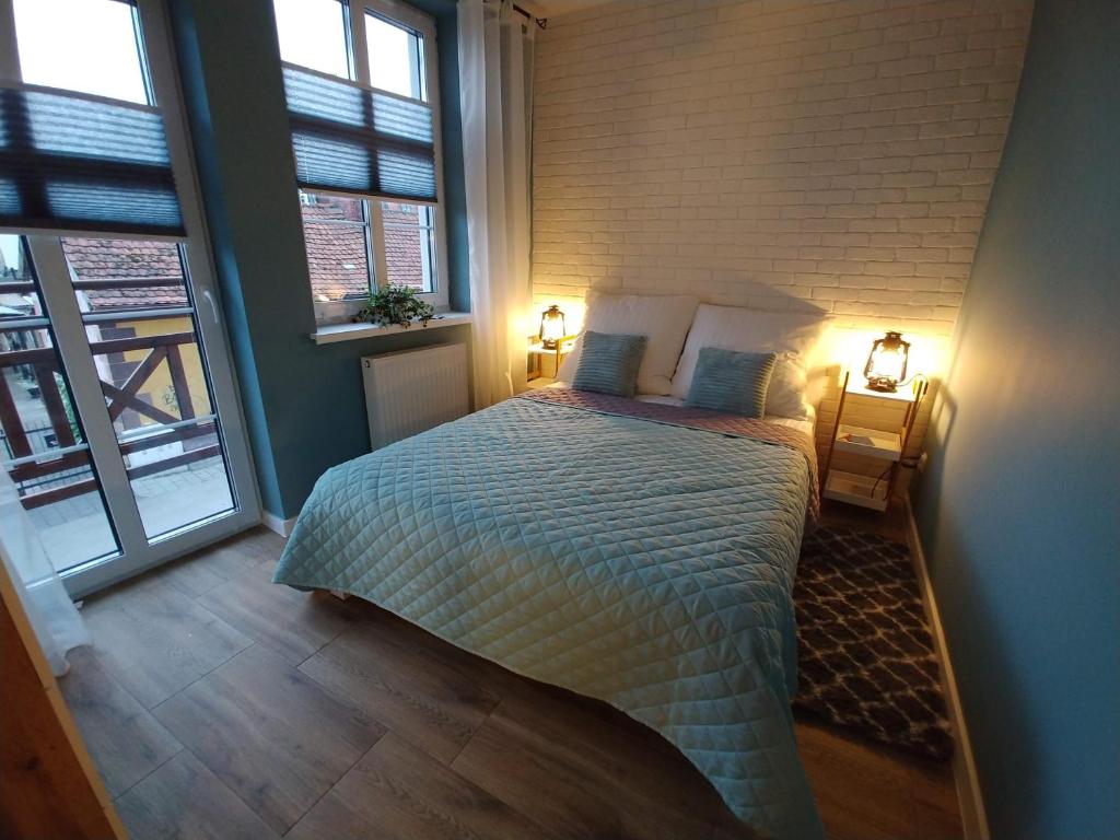 a bedroom with a bed with two lamps and two windows at Willa Lazur in Ustka