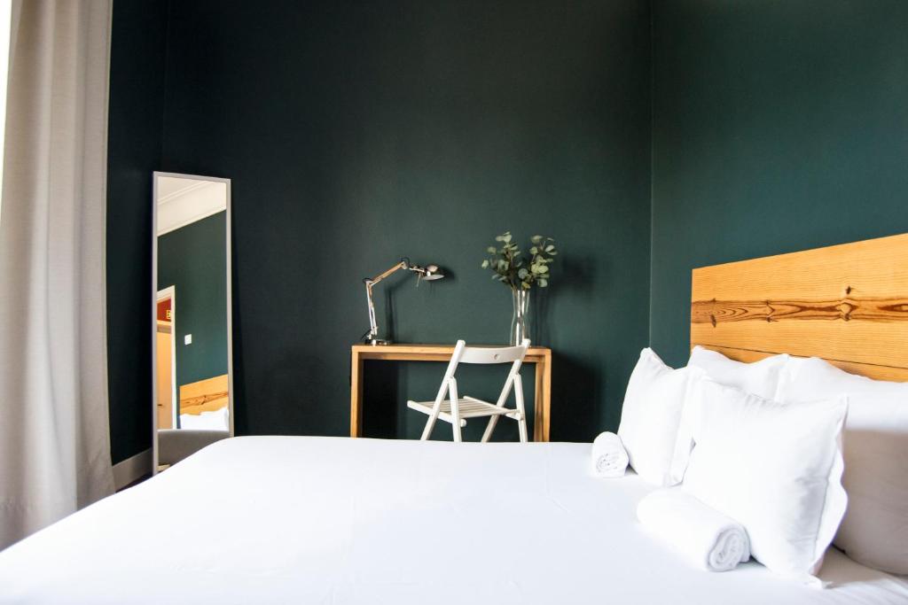 a bedroom with a bed and a desk with a mirror at Avenue Hostel & Suites in Lisbon