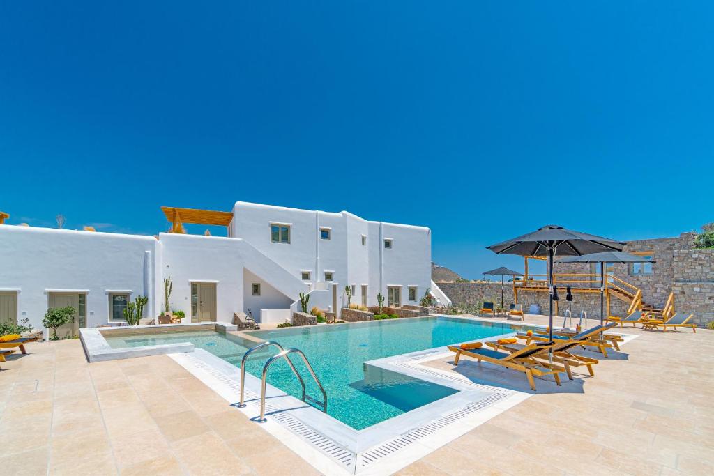 uma piscina com cadeiras e um guarda-sol em frente a um edifício em Mykonos Cactus em Ornos