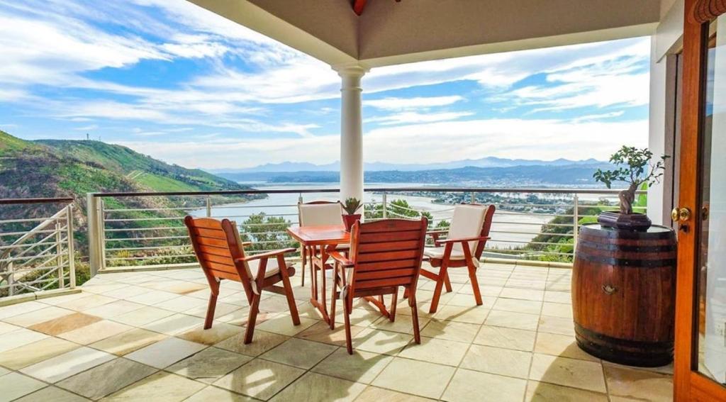 un patio con tavolo, sedie e vista sull'acqua di Knysna Pearl View Guest House a Knysna