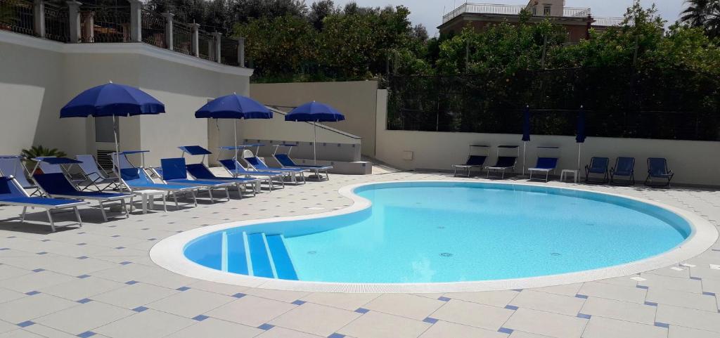- une piscine avec des chaises et des parasols bleus dans l'établissement Central Park, à Massa Lubrense