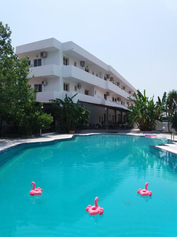 a swimming pool with three inflatable flamingos in the water at Sotirakis Hotel in Faliraki