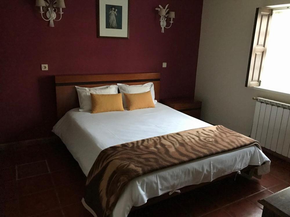 a bedroom with a large bed in a red room at Casas Do Zagão - Turismo Rural in Carregal do Sal