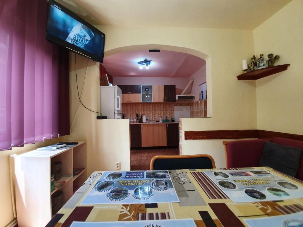 a room with a table and a television and a kitchen at Apartament Maya in Orşova