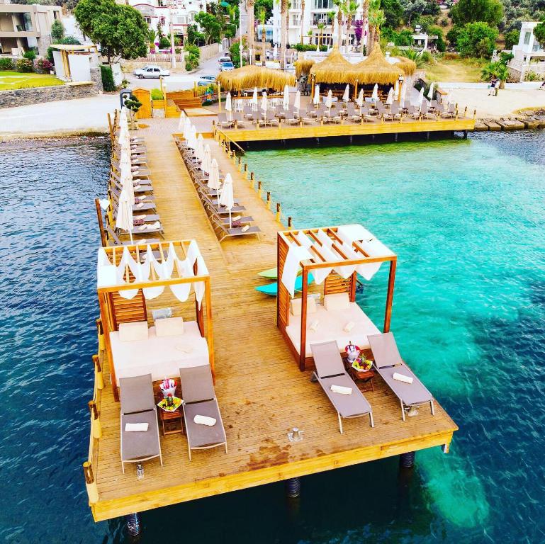 a dock with chairs and tables on the water at Hotel Vita Bella Resort & Spa in Gundogan