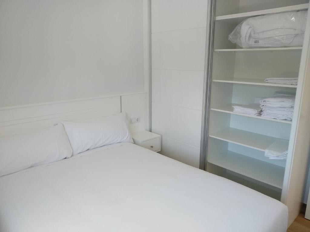 niewielka sypialnia z białym łóżkiem i szafą w obiekcie Casa Da Fonte w mieście Muxia