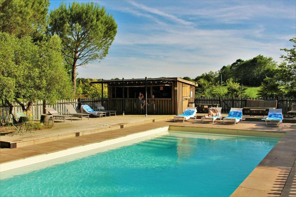 a swimming pool with two lounge chairs and a house at Maison Basta in Orthevielle