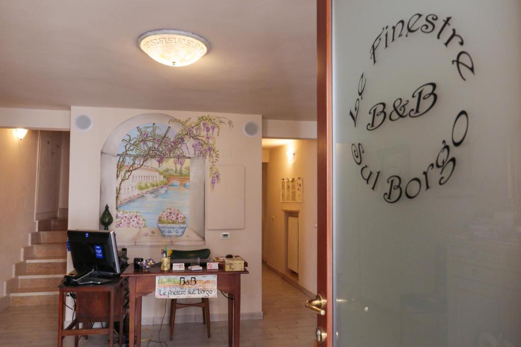 ペスキエーラ・デル・ガルダにあるLe Finestre sul Borgo Roomsのデスクと壁の看板が備わる客室です。
