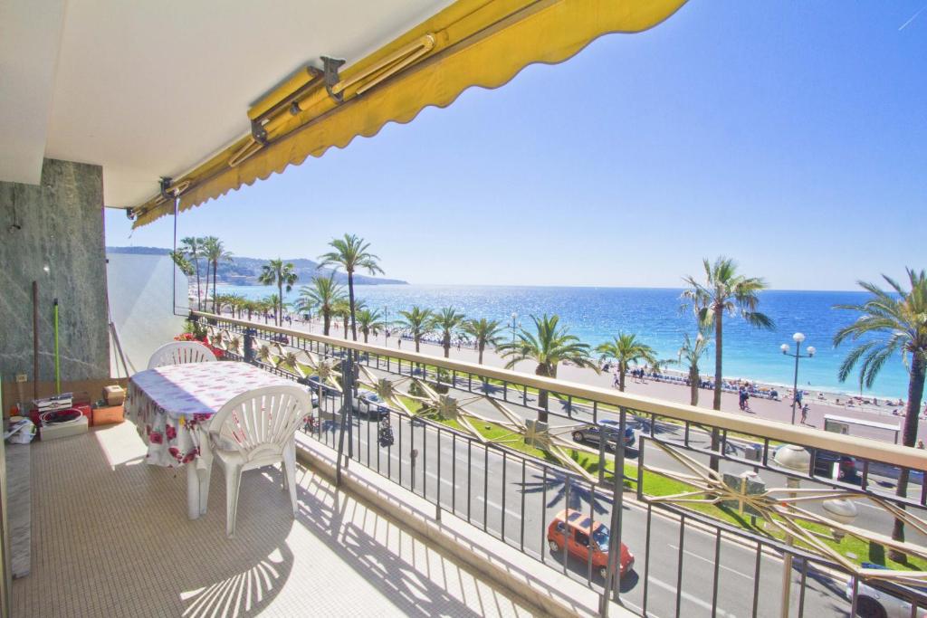 a balcony with a table and a view of the beach at PROMENADE HOLIDAY - SEA FRONT PALATIN in Nice