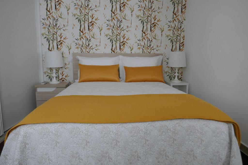 a bedroom with a large bed with two orange pillows at Belo Apartment in Leiria